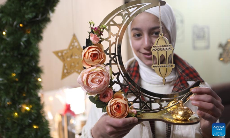 A woman presents wooden decorations at a family workshop ahead of the Islamic holy month of Ramadan, in the West Bank city of Hebron, on March 29, 2022.(Photo: Xinhua)