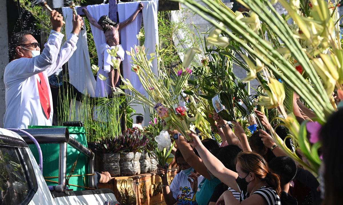 Catholic devotees wave palm fronds as a church layman blesses palms during Palm Sunday celebrations, honoring Jesus Christ's victorious entry into Jerusalem, at the Our Lady of Lourdes Grotto church in San Jose del Monte town, Bulacan Province, northern Manila, the Philippines on April 10, 2022.Photo: AFP