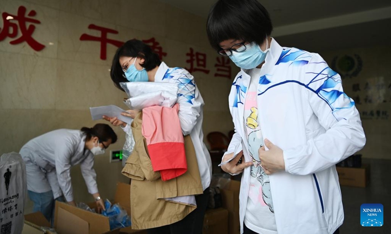 Xu Ning (1st R) puts on team uniform before leaving for Shanghai, in north China's Tianjin, April 11, 2022.(Photo: Xinhua)