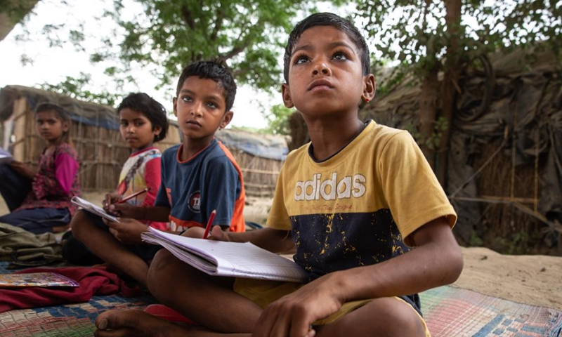 Children study in a makeshift school under a metro bridge in New Delhi, India, April 12, 2022. The free school underneath the metro bridge is run by a group of undergraduate students for children who come from the slums situated adjacent to the Yamuna river.(Photo: Xinhua)