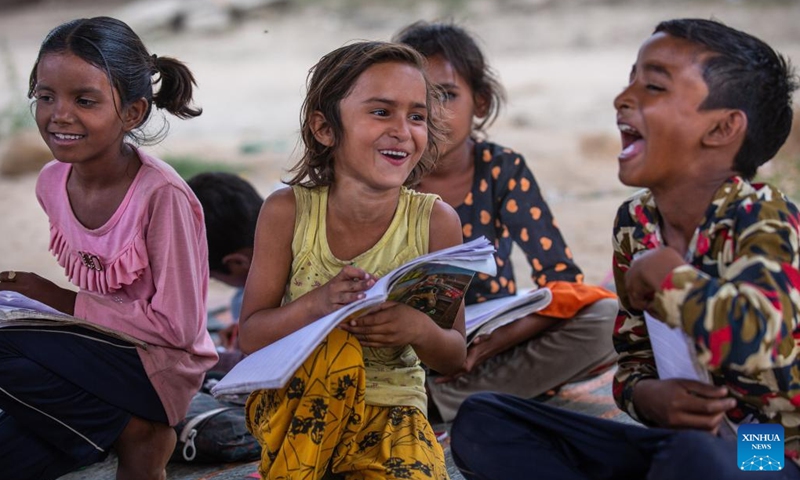 Children study in a makeshift school under a metro bridge in New Delhi, India, April 12, 2022. The free school underneath the metro bridge is run by a group of undergraduate students for children who come from the slums situated adjacent to the Yamuna river.(Photo: Xinhua)