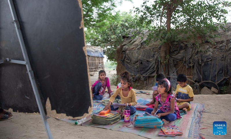 Children study in a makeshift school under a metro bridge in New Delhi, India, April 12, 2022. The free school underneath the metro bridge is run by a group of undergraduate students for children who come from the slums situated adjacent to the Yamuna river.(Photo: Xinhua)