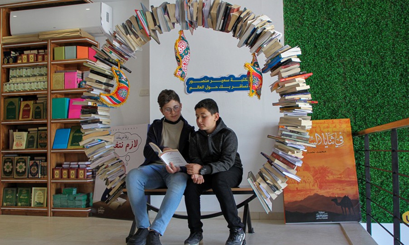 Two Palestinian boys read a book together at the Samir Mansour library in Gaza City, on April 14, 2022.(Photo: Xinhua)