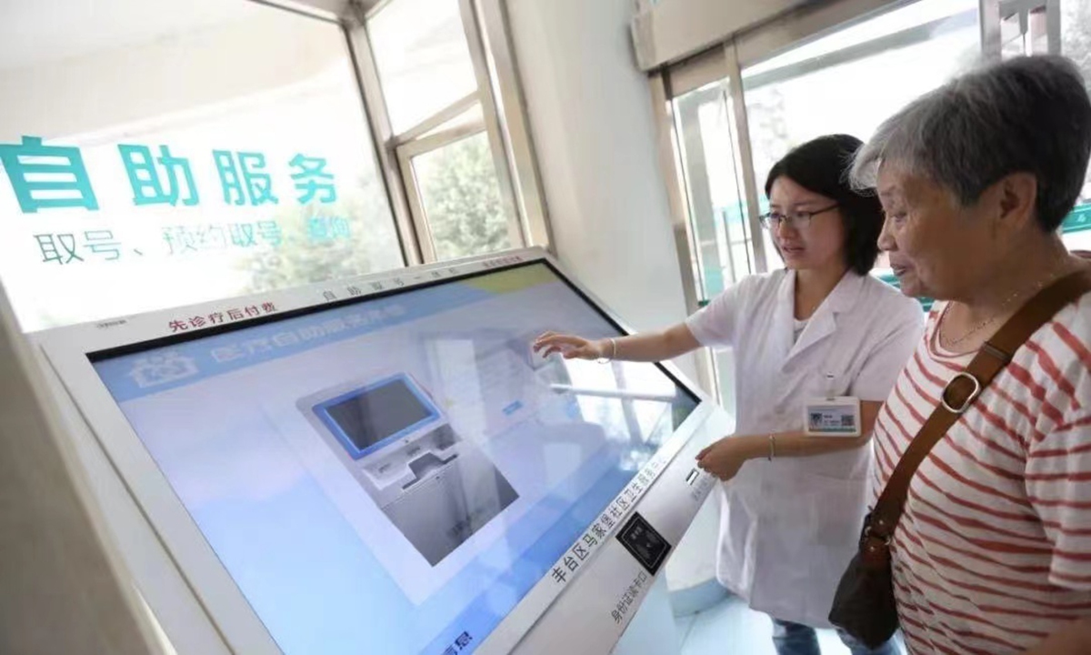 A patient at a hospital in Beijing take numbers of appointment under the guidance of staff.   Source: Beijing Daily