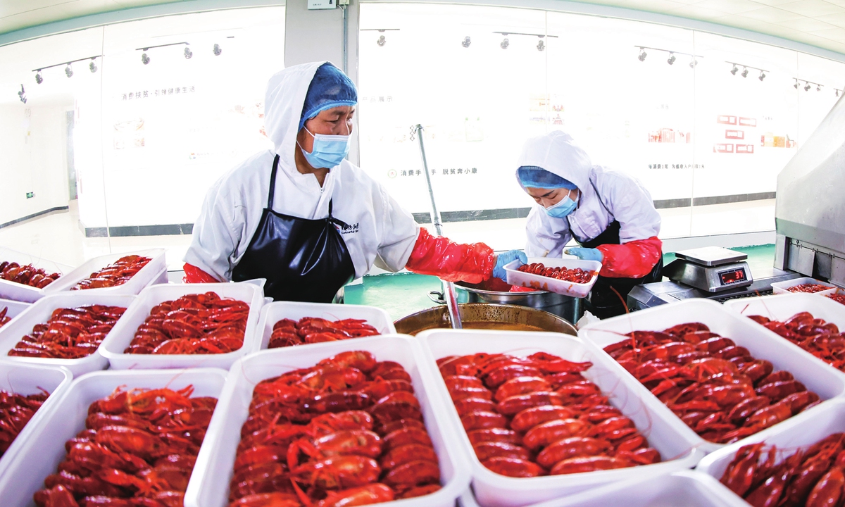 Workers pour sauce on cooked crayfish in a plant in Suqian, East China's Jiangsu Province on May 18, 2022. Crayfish harvest season is starting in the province, and it is a growing industry that helps increase the incomes of local families. Photo: VCG