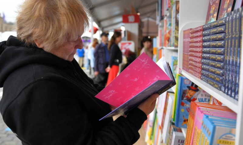 A woman reads a book at the annual book festival on the Red Square in Moscow, Russia, on June 3, 2022. (Photo by Alexander Zemlianichenko Jr/Xinhua)