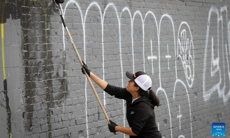 A volunteer covers up graffiti on a wall in Chinatown of Vancouver, British Columbia, Canada, on May 28, 2022.Photo:Xinhua