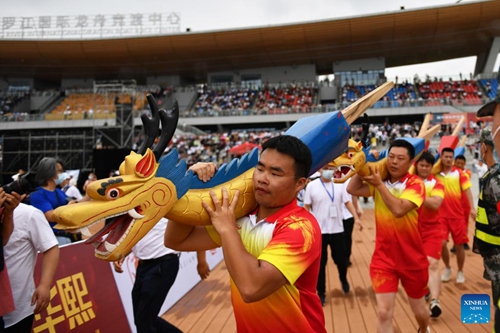 Dragon boat crew members shouldering dragon-head-shaped carvings participate in a ceremony before a traditional Chinese dragon boat race in Miluo City, central China's Hunan Province, June 2, 2022. A dragon boat race including 11 competition teams was held here on the eve of this year's Dragon Boat Festival which will fall on Friday. (Xinhua/Chen Zhenhai)