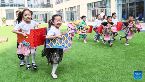 Children equipped with dragon-boat-shaped paper fits take part in a fun game on the eve of the Dragon Boat Festival at a community in Huai'an City, east China's Jiangsu Province, June 2, 2022. The Dragon Boat Festival will fall on June 3 this year. (Photo by Zhao Qirui/Xinhua)

