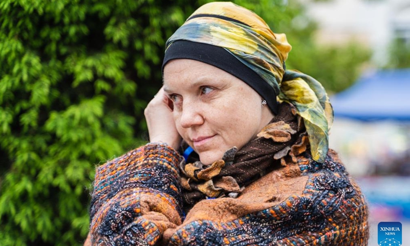 A craftswoman uses her plant-dyed headscarf to imitate the famous painting Girl with a Pearl Earring on a street in Vladivostok, Russia, June 4, 2022.Photo:Xinhua