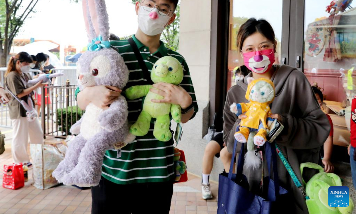 Tourists display purchases outside the World of Disney Store in Shanghai, east China on June 10, 2022. Shanghai Disney Resort partially resumed operations on Friday as the COVID-19 epidemic wanes in the city. Wishing Star Park, the World of Disney Store and Blue Sky Boulevard resumed operations first and Shanghai Disneyland would remain temporarily closed until further notice. Photo:Xinhua