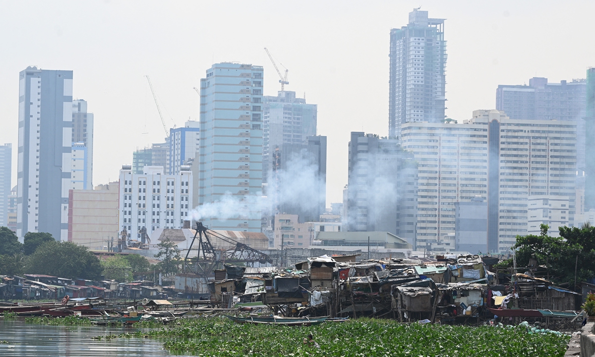 This general view shows high-rise buildings next to low-income houses on stilts erected near a river at the mouth of Manila Bay, the Philippines on June 8, 2022. With a steadily growing metropolitan area, Metro Manila is subject to a densifying population of slum dwellers, with Reuters saying that the city has an estimated 3 million people living in slums. Photo: AFP