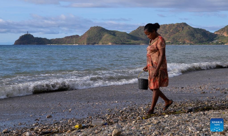 A woman collects stones on a beach in Dili, capital of Timor-Leste, June 6, 2022.(Photo: Xinhua)