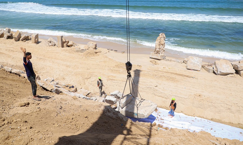 Palestinian engineers and workers use cranes to place concrete blocks to prevent coastal erosion, in Gaza City, on June 9, 2022.(Photo: Xinhua)