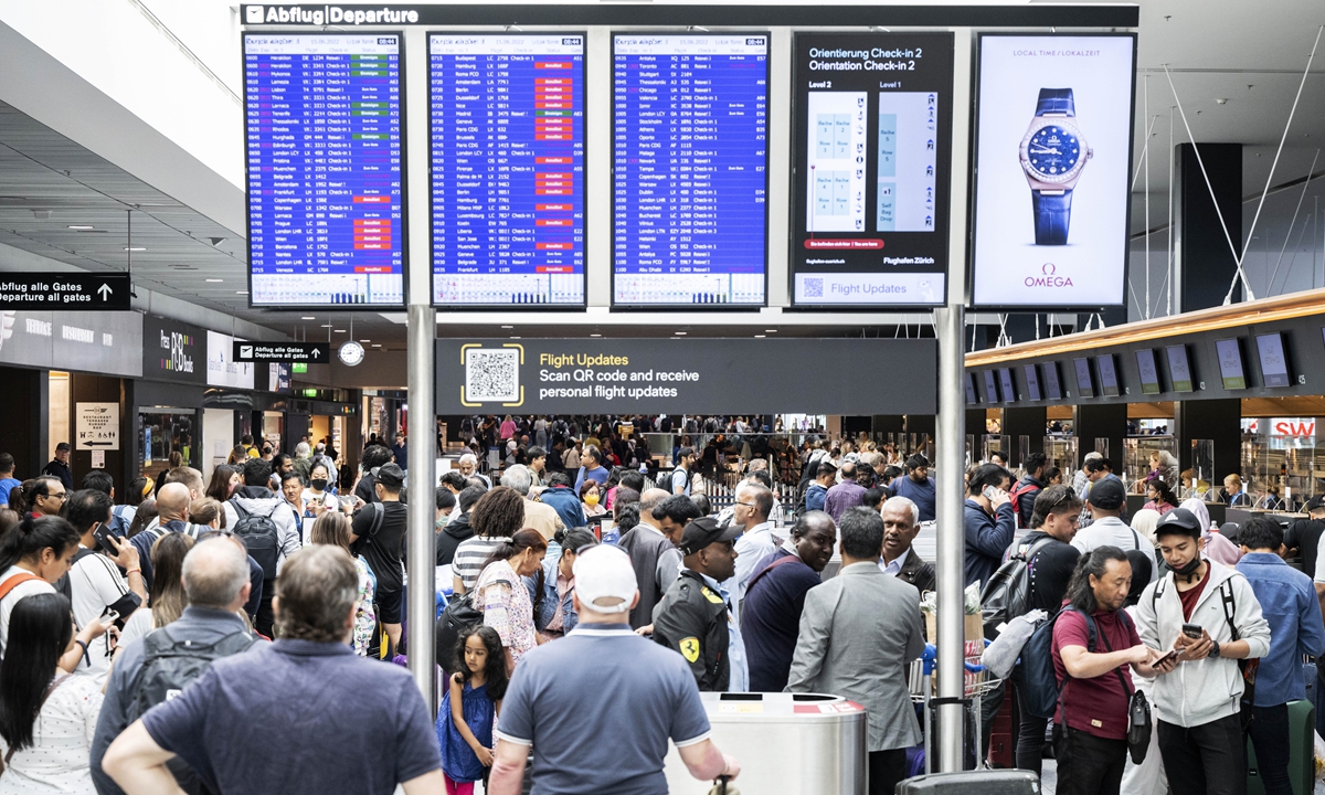 Passengers wait in front of a display board at Zurich airport on Wednesday, June 15, 2022. Switzerland's air traffic controller says Swiss airspace has been reopened after a brief closure for safety reasons due to an unspecified 