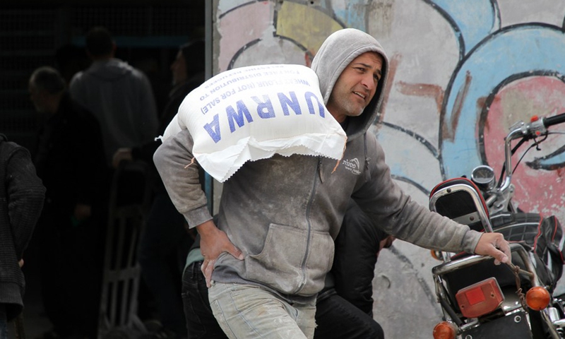 A worker carries a sack of flour at a distribution center of the United Nations Relief and Works Agency for Palestine Refugees in the Near East (UNRWA) at Al-Shati refugee camp in Gaza City, March 20, 2022.(Photo: Xinhua)