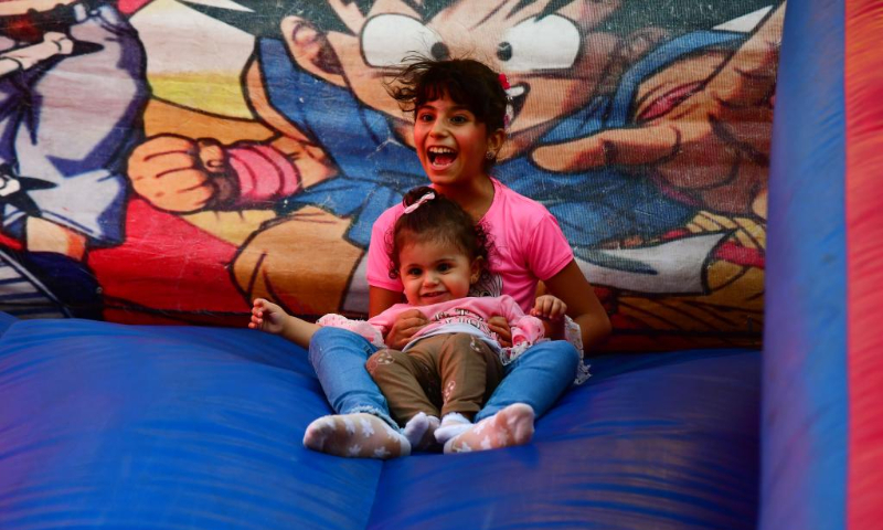 Children play at a theme park in celebration of the Eid al-Adha in Damascus, Syria, on July 9, 2022. (Photo by Ammar Safarjalani/Xinhua)