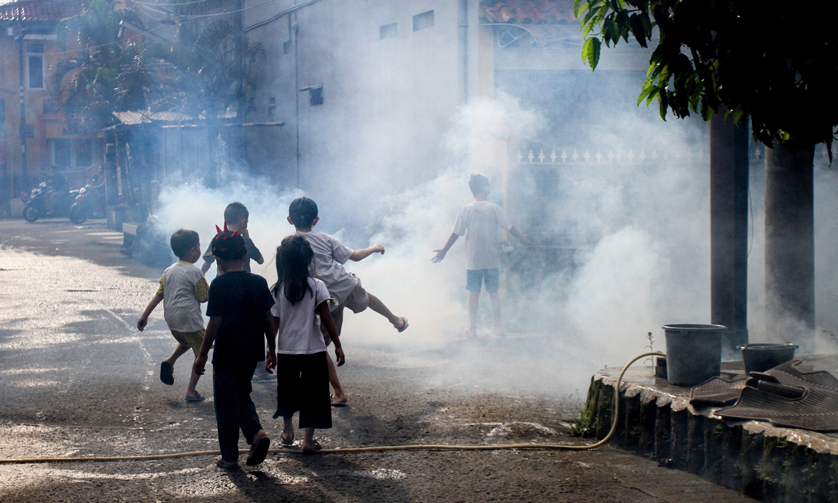 Children play in the vapor as a health worker fumigates a residential area as a preventive measure against dengue fever in Bogor, West Java, Indonesia on June 26, 2022. In 2022 alone, about 86 people have been tested positive, and the majority of them were children, according to local media. Photo: VCG