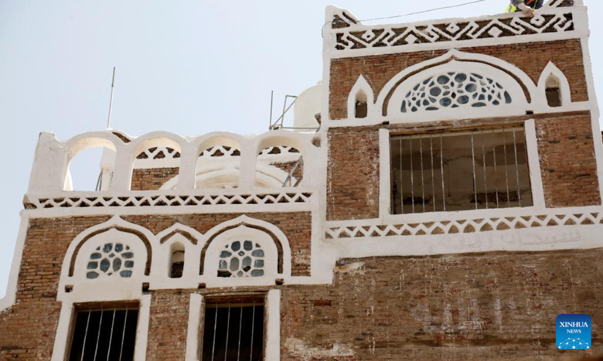 A worker renovates the facade of a house in Old Sanaa City, Yemen, on July 6, 2022. The old city of Sanaa was inscribed on the World Heritage List of the UNESCO in 1986. The old city has been inhabited for more than 2,500 years. The 6,000 mud-brick tower houses are decorated with geometric patterns of white plaster and stained glass windows. Photo:Xinhua