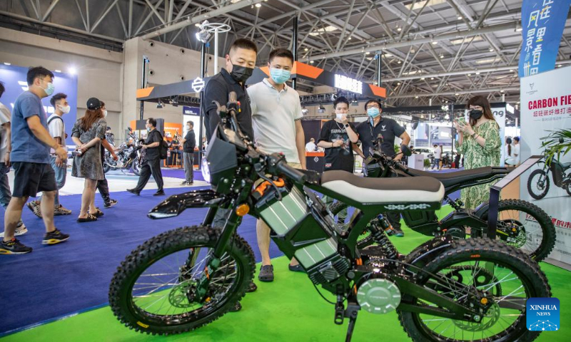 A staff member introduces an electric off-road motorcycle made of ultra-light carbon fiber materials during the 2022 Chongqing International Auto Exhibition in southwest China's Chongqing Municipality, June 25, 2022.