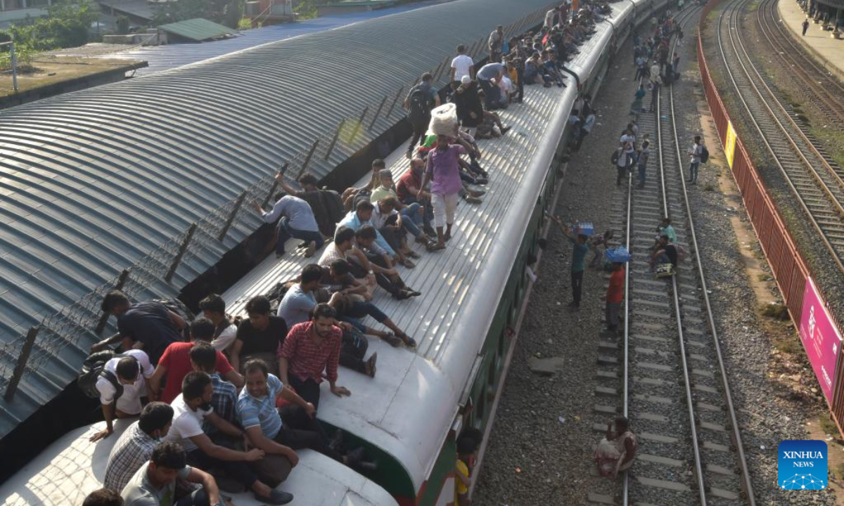 Travelers sitting on the roof of a train leave a station in Dhaka, Bangladesh, July 7, 2022. As Eid al-Adha festival approaches, many people from Bangladesh capital Dhaka have streamed out of the city to join the festival with their kith and kin in village homes. Photo:Xinhua