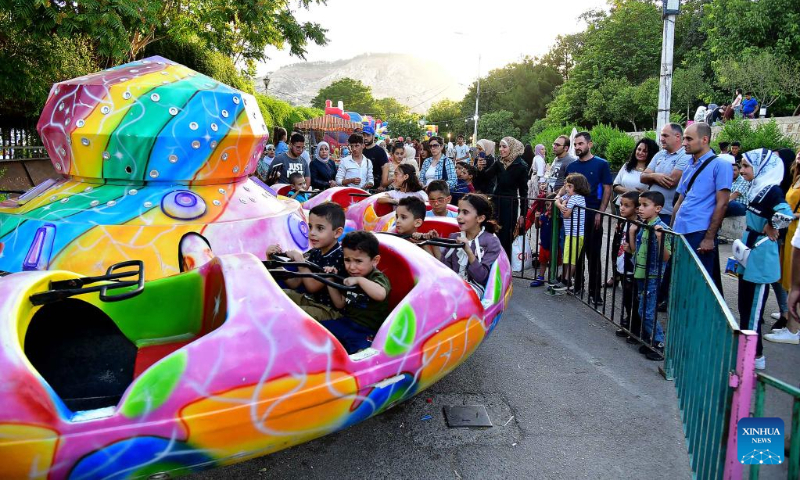 Children play at a theme park in celebration of the Eid al-Adha in Damascus, Syria, on July 9, 2022. (Photo by Ammar Safarjalani/Xinhua)