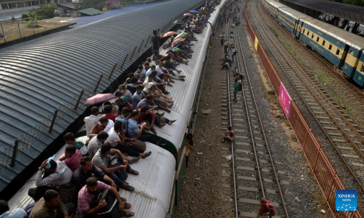 Travelers sitting on the roof of a train leave a station in Dhaka, Bangladesh, July 7, 2022. As Eid al-Adha festival approaches, many people from Bangladesh capital Dhaka have streamed out of the city to join the festival with their kith and kin in village homes. Photo:Xinhua