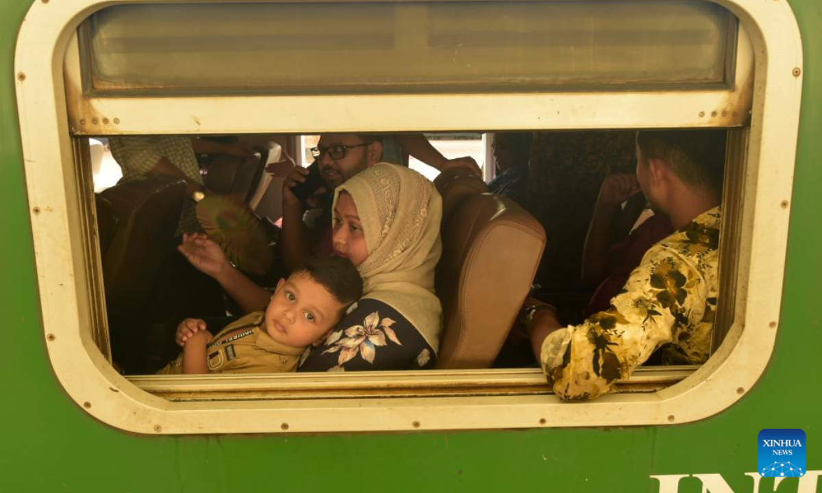 Travelers sitting on a train leave a station in Dhaka, Bangladesh, July 7, 2022. As Eid al-Adha festival approaches, many people from Bangladesh capital Dhaka have streamed out of the city to join the festival with their kith and kin in village homes. Photo:Xinhua