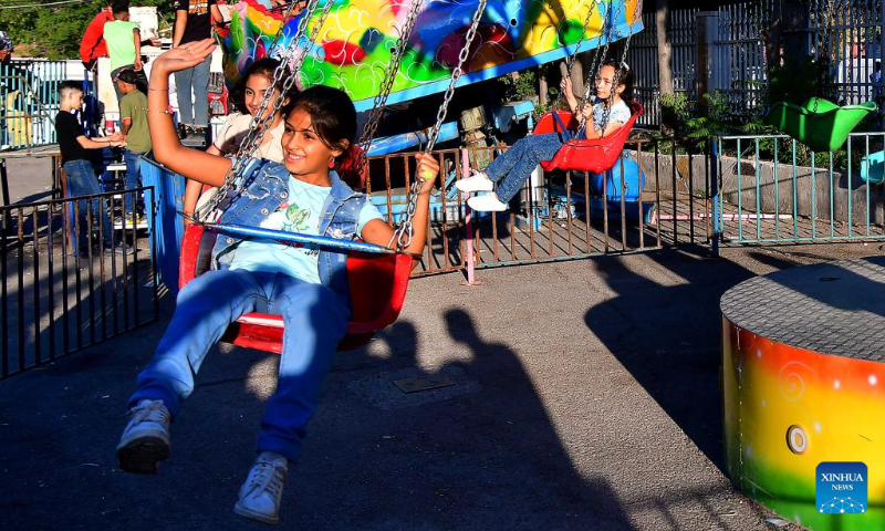 Children play at a theme park in celebration of the Eid al-Adha in Damascus, Syria, on July 9, 2022. (Photo by Ammar Safarjalani/Xinhua)