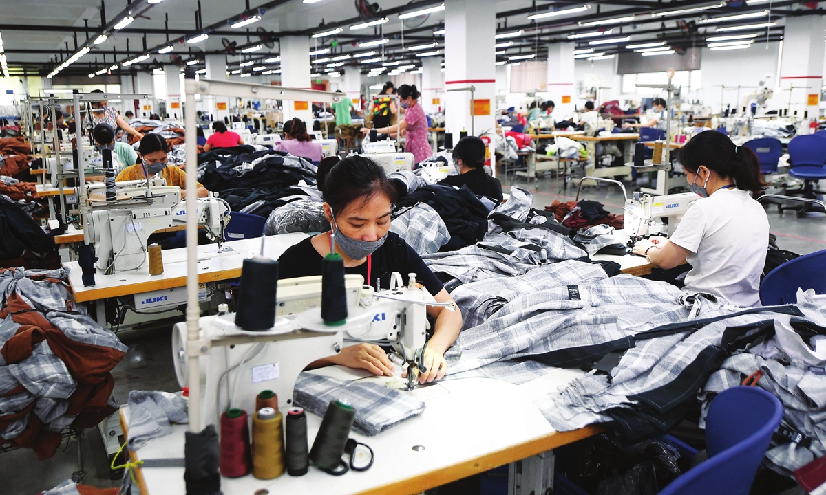 Workers wearing face masks make activewear for various textile clothing brands at a factory in Hanoi. Photo: AFP