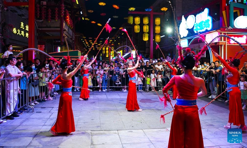 People watch an art performance at a commercial street in southwest China's Chongqing Municipality, June 1, 2022.Photo:Xinhua