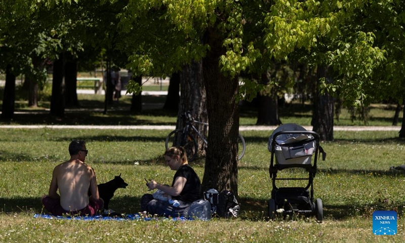 People rest in the shade of a tree from the sun at a park in Ljubljana, capital of Slovenia, July 3, 2022.Photo:Xinhua