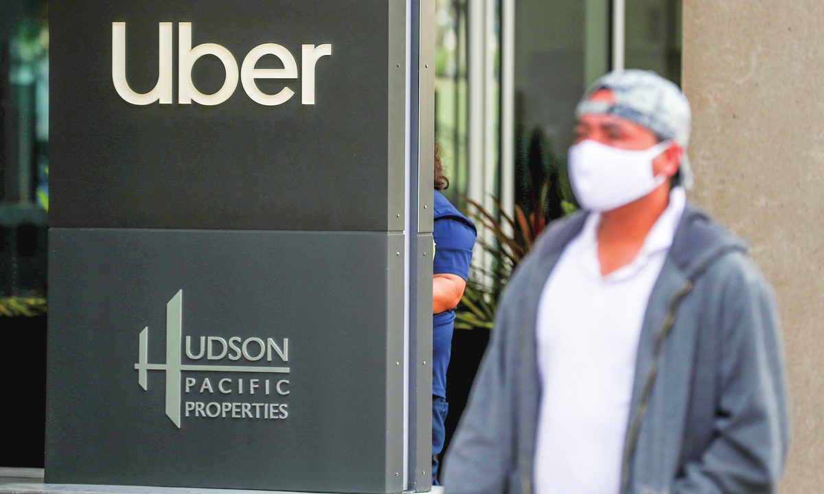 A pedestrian walks by a sign in front of Uber's headquarters in San Francisco, California. Photo:VCG