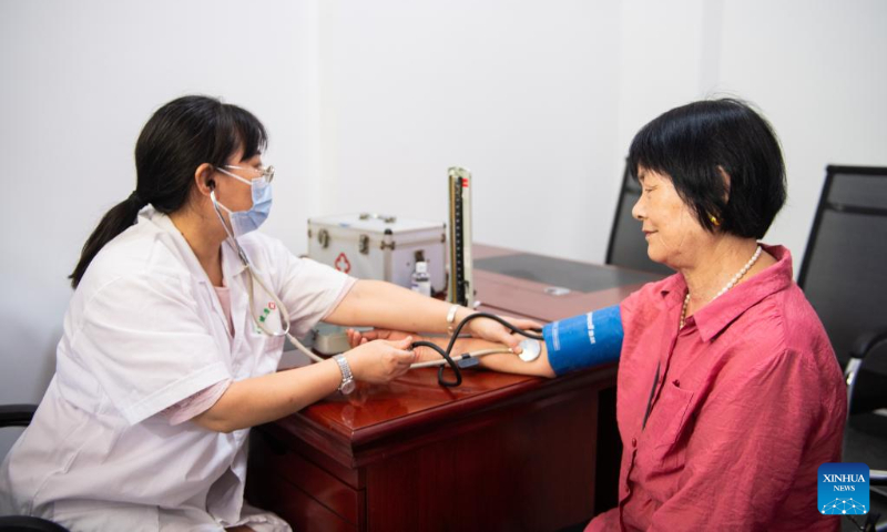 A medical worker checks blood pressure of a senior citizen at a community-based day-care center in Hanshou County, central China's Hunan Province, July 20, 2022. (Xinhua/Chen Sihan)