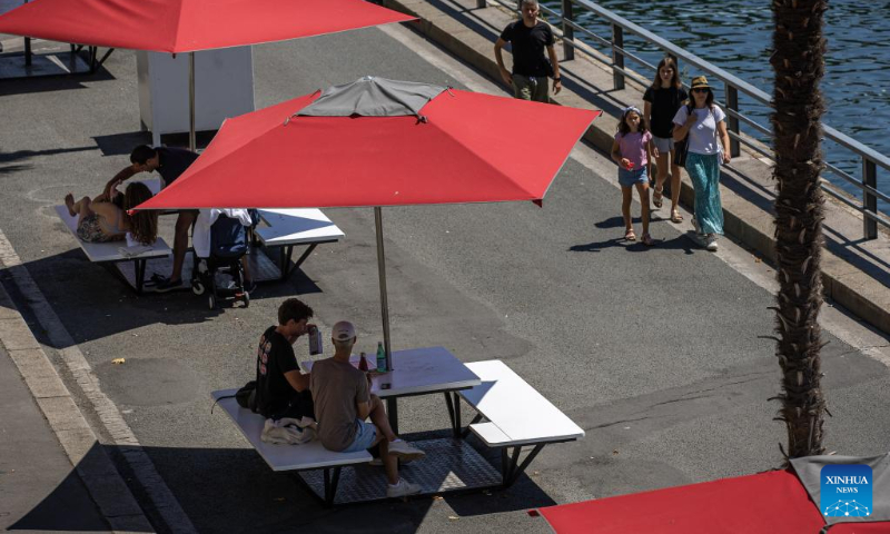 People enjoy the annual Paris Plages city beach event along the bank of the Seine in Paris, France, July 11, 2022. The Paris Plages city beach event is held from July 9 to Aug. 21 this year, offering events and activities on the banks of the Seine and the Bassin de la Villette. (Photo by Aurelien Morissard/Xinhua)