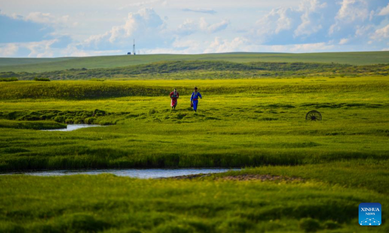 Two young people walk by a river in West Ujimqin Banner of Xilingol League, north China's Inner Mongolia Autonomous Region, July 19, 2022. (Xinhua/Peng Yuan)