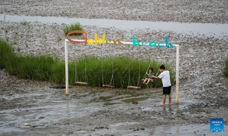 A kid enjoys a swing ride on a beach in Qidong, east China's Jiangsu Province, July 16, 2022. (Xinhua/Ji Chunpeng)