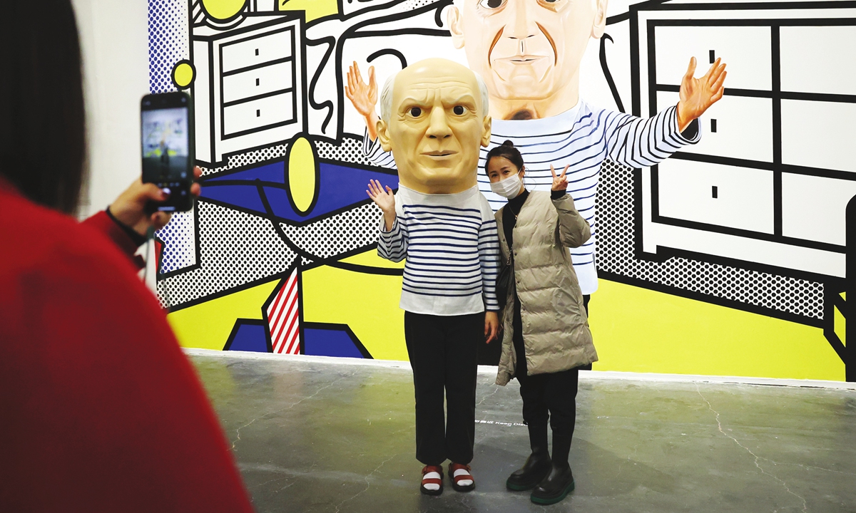 A visitor (right) poses for a picture at a 2021 Maurizio Cattelan exhibition in Beijing. Photo: VCG 