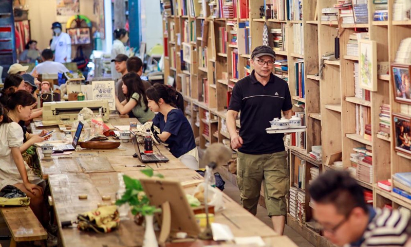 A bookstore owner serves readers tea in a bookstore renovated from a former air-raid shelter in Jiulongpo District of southwest China's Chongqing, July 11, 2022. As Chongqing is sweltering in a heatwave, locals turn to different places to escape the scorching heat.(Photo: Xinhua)