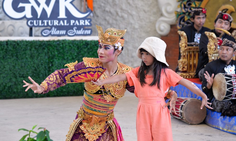 A dancer interacts with a girl during a traditional Balinese dance performance in a cultural park in Bali, Indonesia, on July 10, 2022.(Photo: Xinhua)