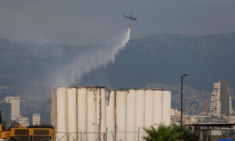 A helicopter dumps water on the Beirut port grain silos after its northern part collapsed in Beirut, Lebanon, July 31, 2022. The northern part of the Beirut port grain silos collapsed on Sunday after being on fire for weeks, causing a huge cloud of dust, the National News Agency reported.  Photo: Xinhua