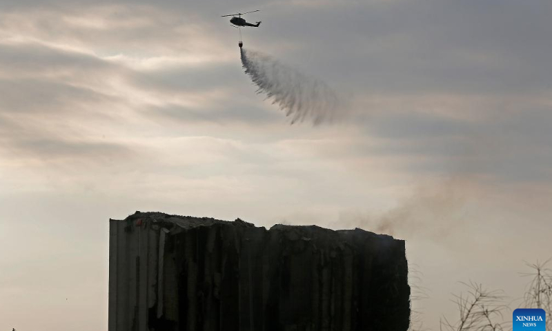 A helicopter dumps water on the Beirut port grain silos after its northern part collapsed in Beirut, Lebanon, July 31, 2022. The northern part of the Beirut port grain silos collapsed on Sunday after being on fire for weeks, causing a huge cloud of dust, the National News Agency reported. Photo: Xinhua