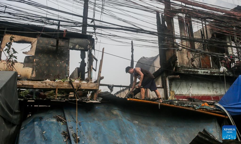 A resident searches for reusable materials from charred homes after a fire at a residential area in Manila, the Philippines, Aug. 3, 2022. Some 500 families lost their homes in the fire, according to local media.(Photo: Xinhua)