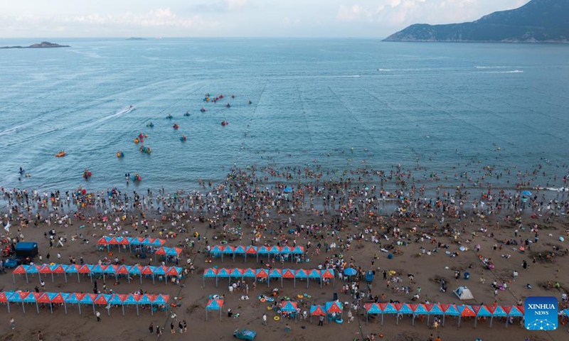 Aerial photo taken on Aug. 2, 2022 shows tourists enjoying seaside time in Zhujiajian scenic spot in Zhoushan, east China's Zhejiang Province. Zhujiajian scenic spot has provided various seaside entertainments for tourists to boost tourism during the summer vacation.(Photo: Xinhua)