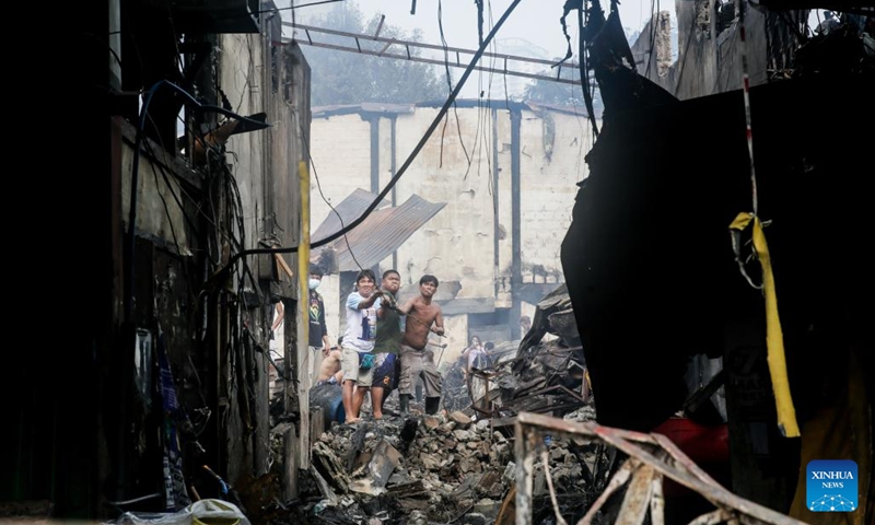 Residents try to topple a weakened wall after a fire at a residential area in Manila, the Philippines, Aug. 3, 2022. Some 500 families lost their homes in the fire, according to local media.(Photo: Xinhua)