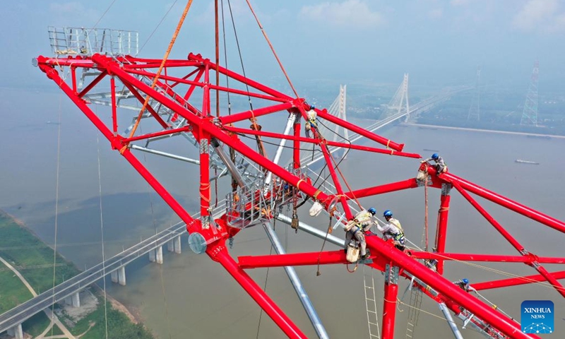 Aerial photo shows laborers working at the construction site of a long span transmission tower of Baihetan-Zhejiang ultra-high-voltage (UHV) power transmission project by the Yangtze River in Chizhou, east China's Anhui Province, Aug. 1, 2022. Construction of the main structure of a 345-meter-high long span transmission tower of Baihetan-Zhejiang UHV power transmission project was completed here Monday. (Photo by Zhao Xianfu/Xinhua)