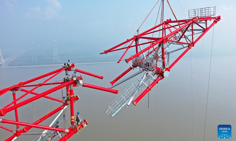 Aerial photo shows laborers working at the construction site of a long span transmission tower of Baihetan-Zhejiang ultra-high-voltage (UHV) power transmission project by the Yangtze River in Chizhou, east China's Anhui Province, Aug. 1, 2022. Construction of the main structure of a 345-meter-high long span transmission tower of Baihetan-Zhejiang UHV power transmission project was completed here Monday. (Photo by Zhao Xianfu/Xinhua)