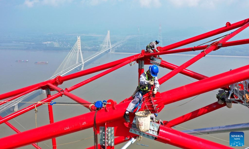 Aerial photo shows laborers working at the construction site of a long span transmission tower of Baihetan-Zhejiang ultra-high-voltage (UHV) power transmission project by the Yangtze River in Chizhou, east China's Anhui Province, Aug. 1, 2022. Construction of the main structure of a 345-meter-high long span transmission tower of Baihetan-Zhejiang UHV power transmission project was completed here Monday. (Photo by Zhao Xianfu/Xinhua)