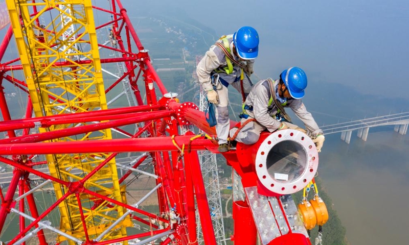 Aerial photo shows laborers working at the construction site of a long span transmission tower of Baihetan-Zhejiang ultra-high-voltage (UHV) power transmission project by the Yangtze River in Chizhou, east China's Anhui Province, Aug. 1, 2022. Construction of the main structure of a 345-meter-high long span transmission tower of Baihetan-Zhejiang UHV power transmission project was completed here Monday. (Photo by Zheng Xianlie/Xinhua)