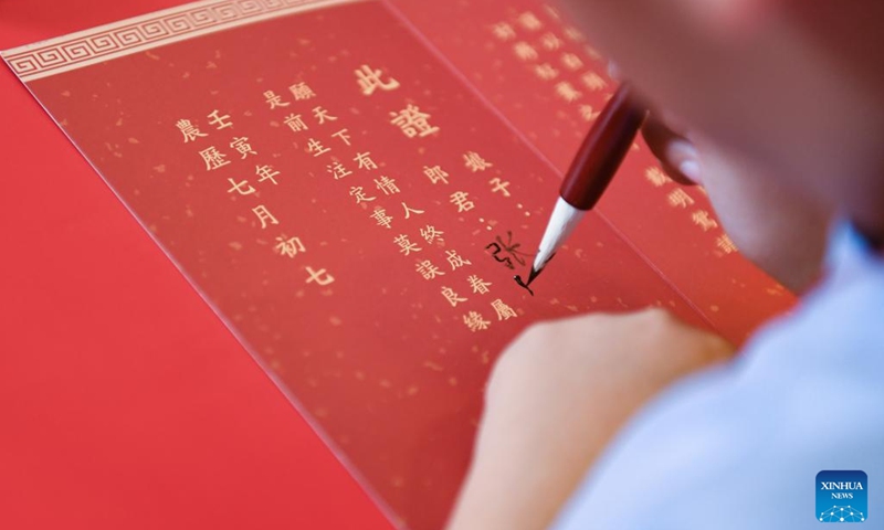 A tourist writes a marriage certificate on the occasion of Qixi Festival in Qujiang New District in Xi'an, northwest China's Shaanxi Province, Aug. 4, 2022. The Qixi Festival, or Chinese Valentine's Day, falls on Aug. 4 this year. (Photo by Zou Jingyi/Xinhua)